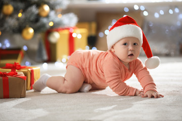 Obraz na płótnie Canvas Little baby wearing Santa hat on floor indoors. First Christmas