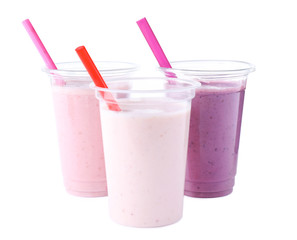 Tasty fresh milk shakes in plastic cups on white background