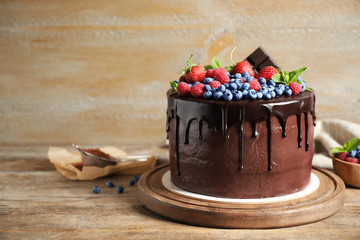 Freshly made delicious chocolate cake decorated with berries on wooden table