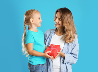 Little daughter congratulating her mom on blue background. Happy Mother's Day