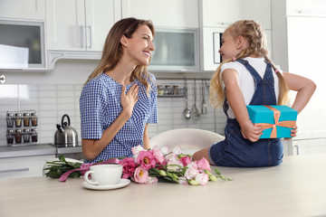 Little daughter congratulating her mom in kitchen. Happy Mother's Day