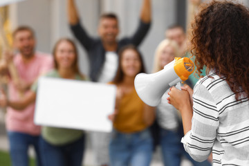 Female meeting leader with megaphone talking to crowd outdoors