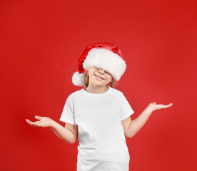 Cute little child wearing Santa hat on red background. Christmas holiday