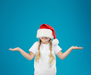 Fototapeta na wymiar Cute little child wearing Santa hat on blue background. Christmas holiday