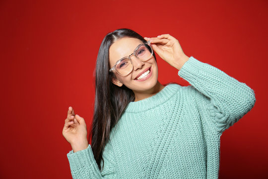 Young woman in warm sweater on red background