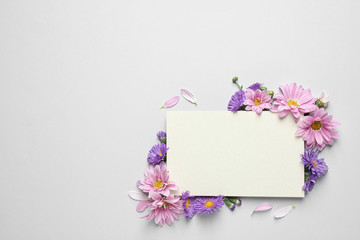 Beautiful chamomile flowers and paper card on white background, flat lay with space for text