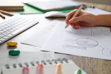 Female designer working at wooden table, closeup