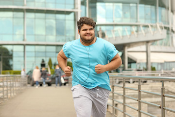 Young overweight man running outdoors. Fitness lifestyle