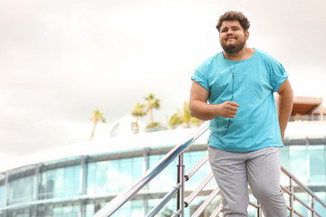 Young overweight man in sportswear outdoors. Fitness lifestyle - obrazy, fototapety, plakaty