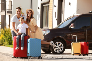 Happy family with suitcases near house outdoors. Moving day