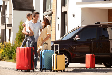 Happy family with suitcases near house outdoors. Moving day