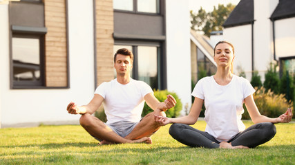Sporty couple practicing morning yoga at backyard. Healthy lifestyle