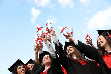 Happy students with diplomas outdoors. Graduation ceremony