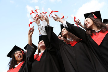 Happy students with diplomas outdoors. Graduation ceremony