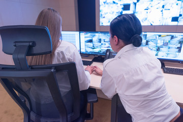 Security guard monitoring modern CCTV cameras in surveillance room. Two Female security guards in surveillance room.
