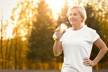 Sporty mature woman with bottle of water outdoors