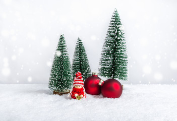Fototapeta na wymiar Christmal doll in red sweater with bell, fir trees and ornaments