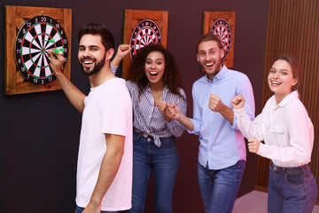 Group of friends playing darts in bar