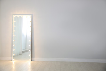 Large mirror with light bulbs near light wall indoors. Interior element