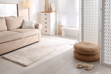 Stylish room interior with white folding screen and sofa