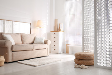 Stylish room interior with white folding screen and sofa