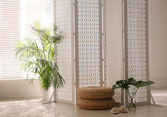 Stylish room interior with white folding screen and plants