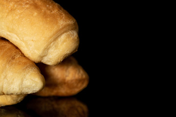 Group of four whole fresh baked mini croissant closeup isolated on black glass