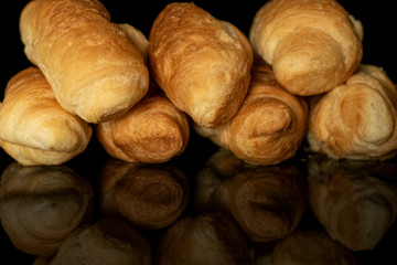 Group of seven whole fresh baked mini croissant isolated on black glass