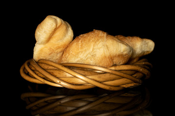 Group of three whole fresh baked mini croissant in wicker vine circle isolated on black glass