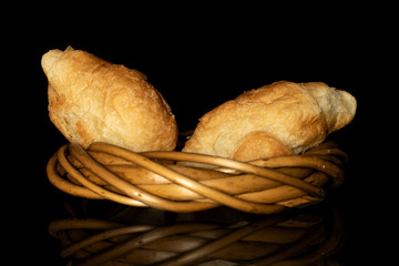 Group of two whole fresh baked mini croissant in wicker vine circle isolated on black glass