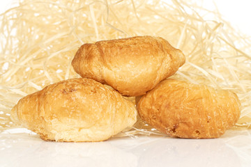 Group of three whole fresh baked mini croissant with straw isolated on white background