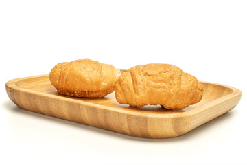 Group of two whole fresh baked mini croissant on wooden square plate isolated on white background