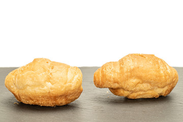 Group of two whole fresh baked mini croissant on grey stone isolated on white background