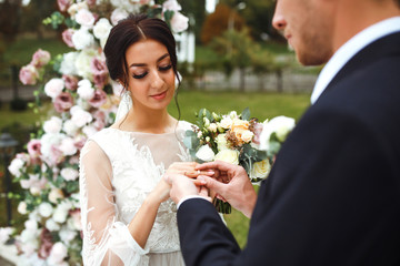 Wedding engagement rings. Married couple exchange wedding rings at a wedding ceremony. Groom put a...