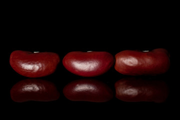 Group of three whole fresh red kidney beans isolated on black glass