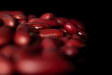 Lot of whole ripe fresh red kidney beans isolated on black glass