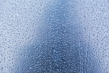 Water droplets or Rain Drops On Glass Textured Blue Background.