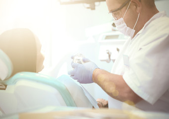 Image of young lady with dentist over her before checking oral cavity