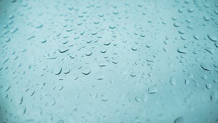 Water drops from the rain on the glass with blue tones