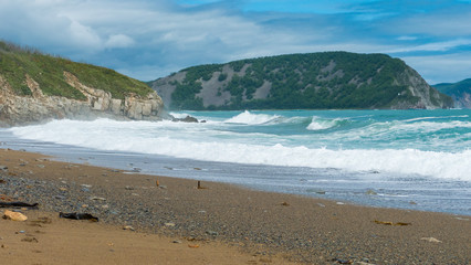 Fototapeta na wymiar sea shore big waves foam and sun on the background of rocks
