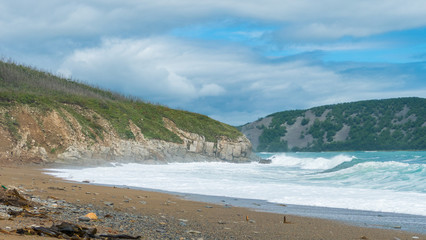 sea shore big waves foam and sun on the background of rocks