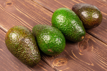 Group of four whole fresh green avocado on brown wood