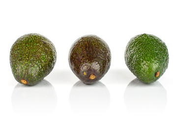 Group of three whole fresh green avocado in row isolated on white background