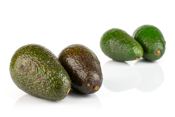 Group of four whole fresh green avocado placed in two groups isolated on white background
