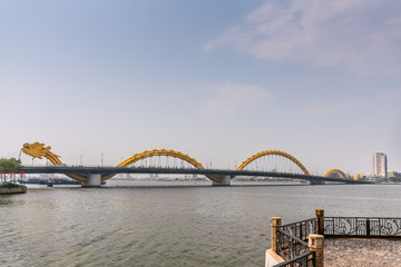 Da Nang, Vietnam - March 10, 2019: Shot from love bridge over wide Han River on Cau Rong or Dragon bridge on horizon under morning sky.