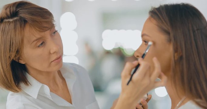 Makeup artist completes makeup, woman thanks makeup artist. Beauty Studio. Portrait view.