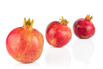 Group of three whole fresh red pomegranate placed diagonally isolated on white background