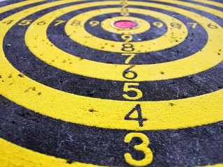 Target for throwing Darts. Black and yellow concentric circles with digital markings and dart marks. Goal achievement symbol. Abstract background. Empty space.