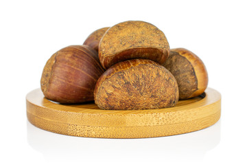 Group of five whole sweet brown chestnut on bamboo coaster isolated on white background