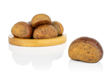 Group of six whole sweet brown chestnut on bamboo coaster isolated on white background